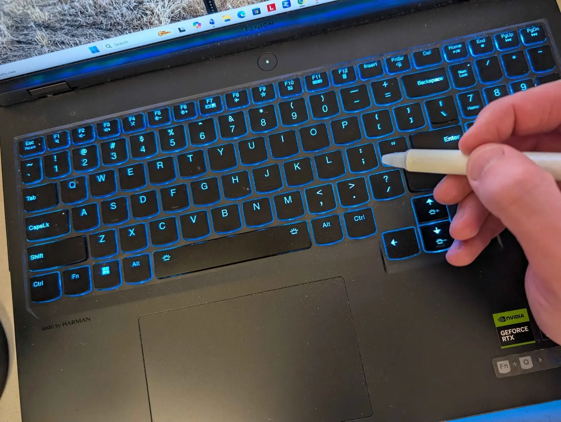 A writer is busy writing on his keyboard with a pen.